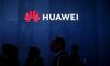 Attendees walk past signage displayed outside the Huawei Technologies Co. booth at the 2019 Consumer Electronics Show (CES) in Las Vegas.