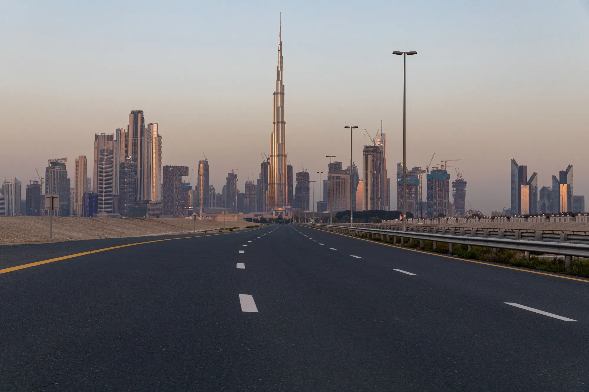 An empty highway leads towards the Burj Khalifa skyscraper, center, and other office buildings on the city skyline in Dubai.