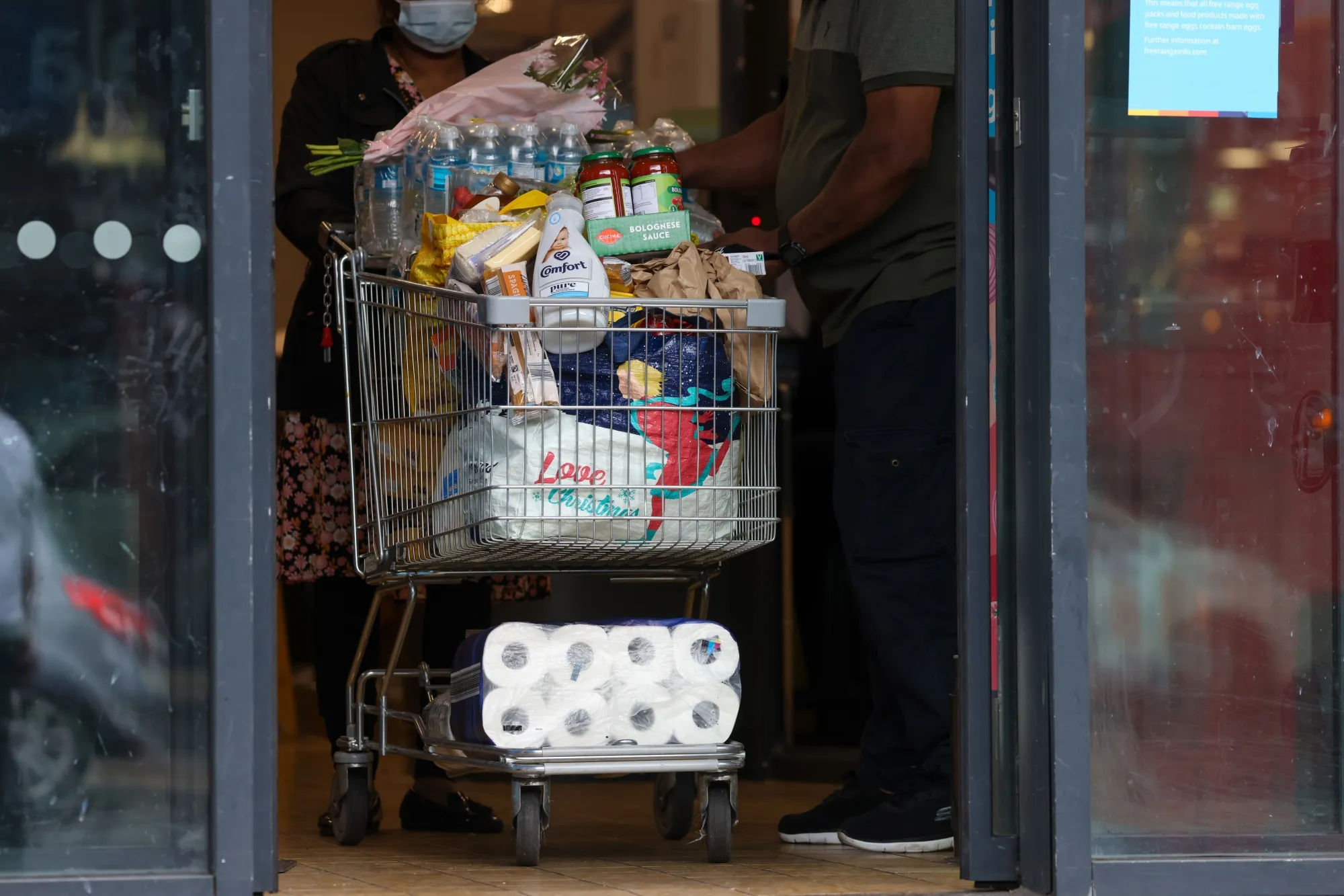 A customer pushes a shopping trolley full of groceries a supermarket&nbsp;in London.