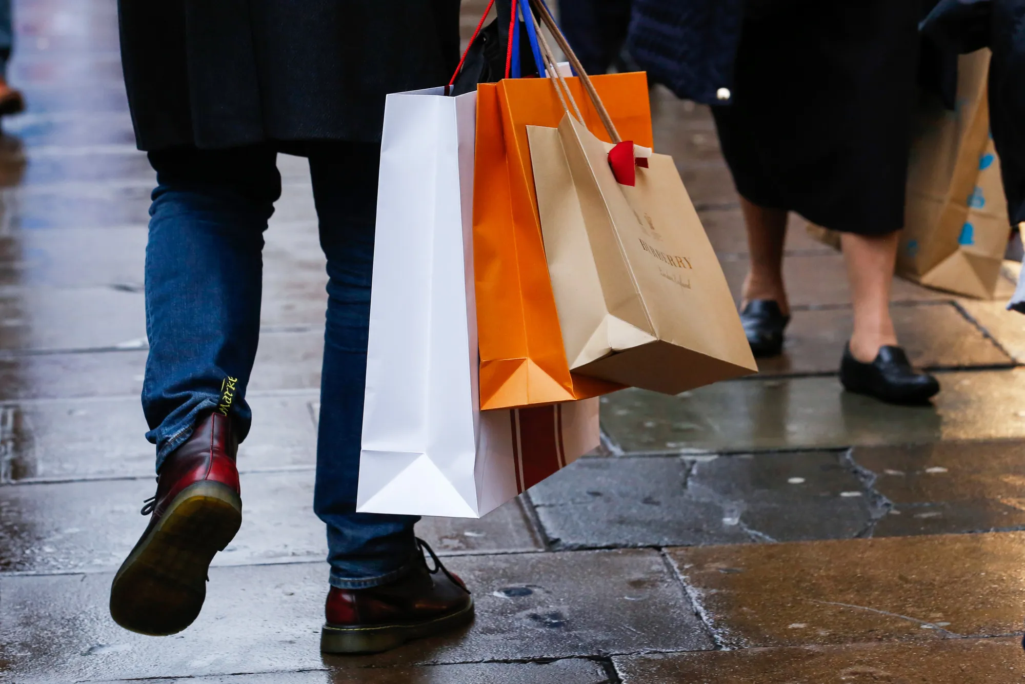 A shopper carries bags while walking along on Oxford Street in central London, U.K., on Tuesday, Nov. 7, 2017. U.K. retail sales fell the most in seven months in October, indicating continued caution among consumers just weeks before the crucial Christmas shopping season.