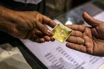 An employee hands a 50-gram gold bar to a customer inside a&nbsp;jewelry store&nbsp;in Mumbai.