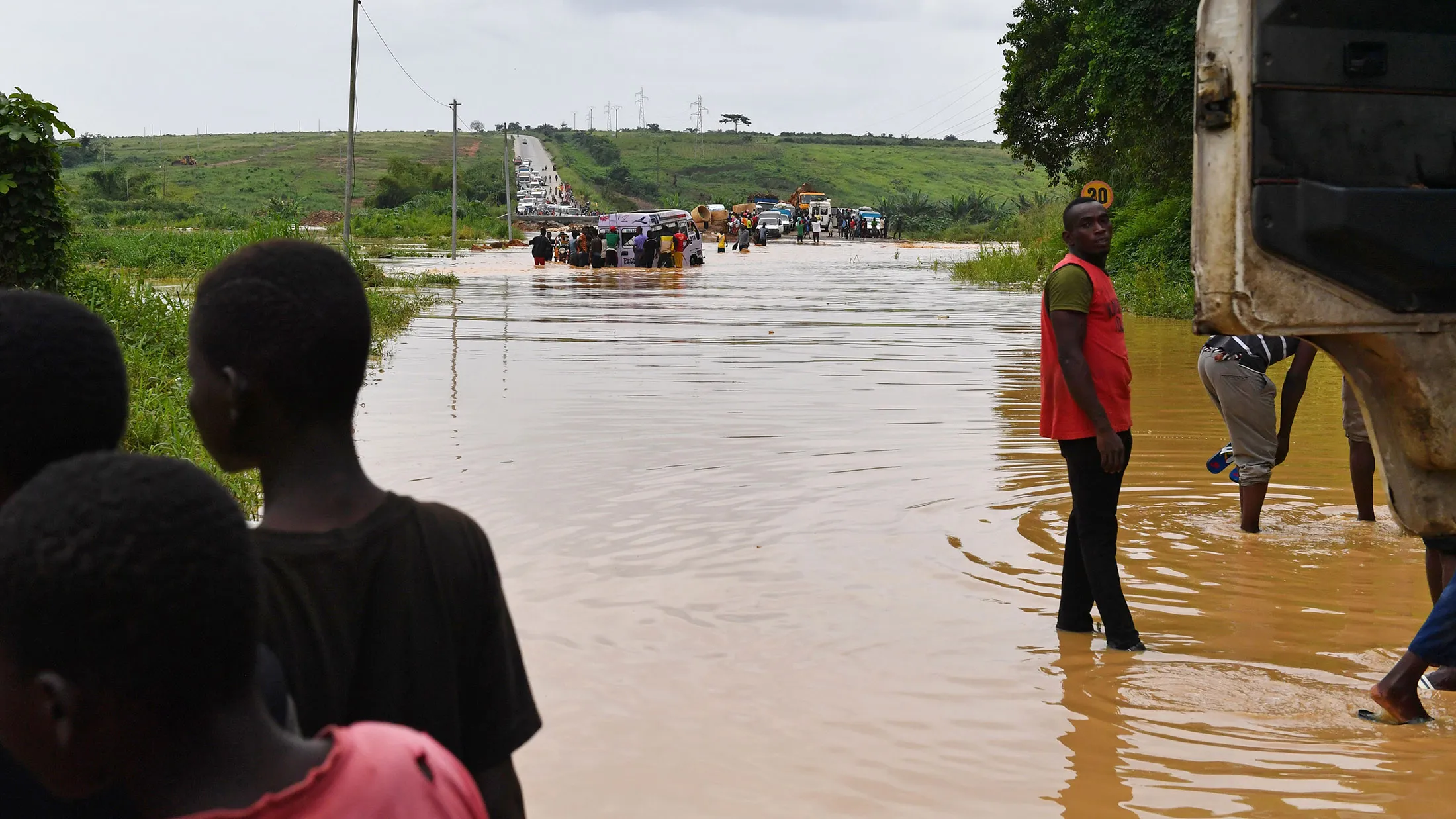 People attempt to push a car across a river, close to Abidjan, on May 25, 2017 following torrential rains. / AFP PHOTO / ISSOUF SANOGO (Photo credit should read ISSOUF SANOGO/AFP/Getty Images)
