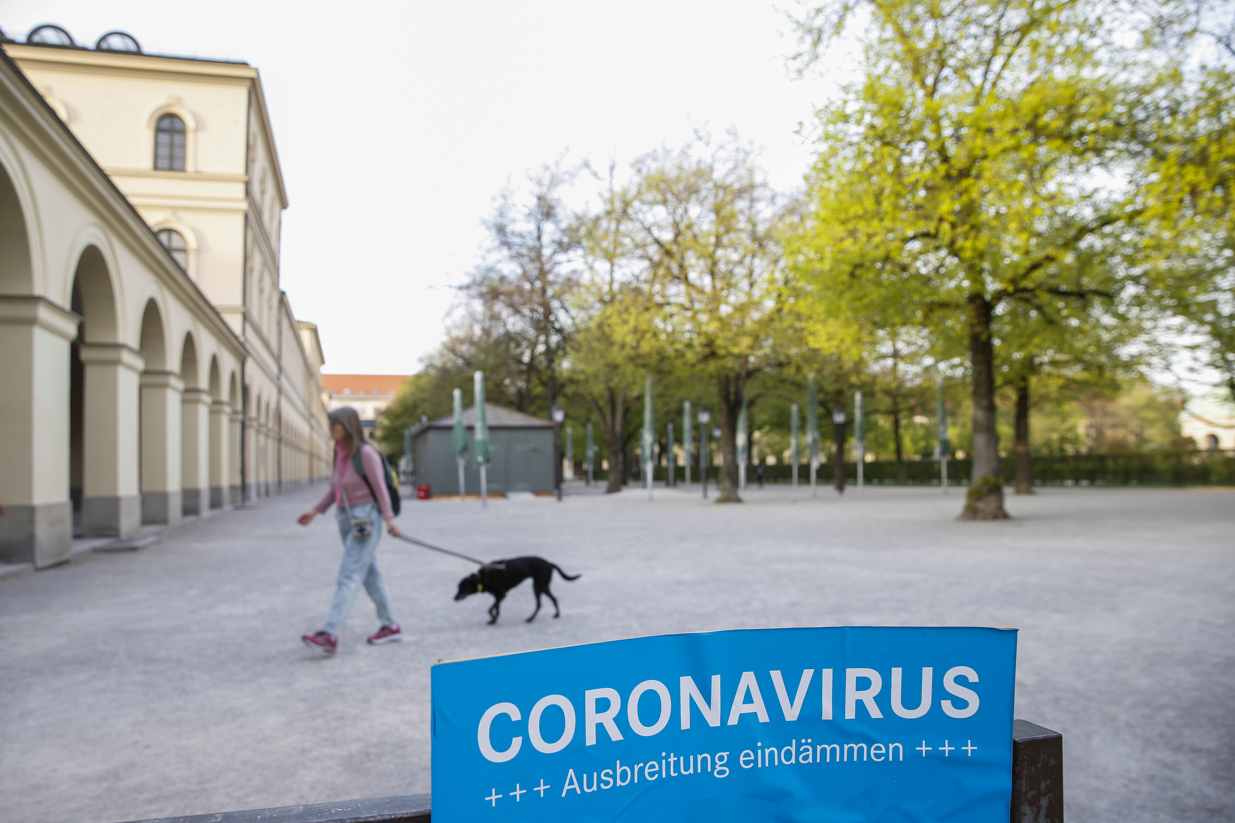 A dog walker passes a coronavirus information sign during lockdown in Munich, Germany, on&nbsp;April 16.
