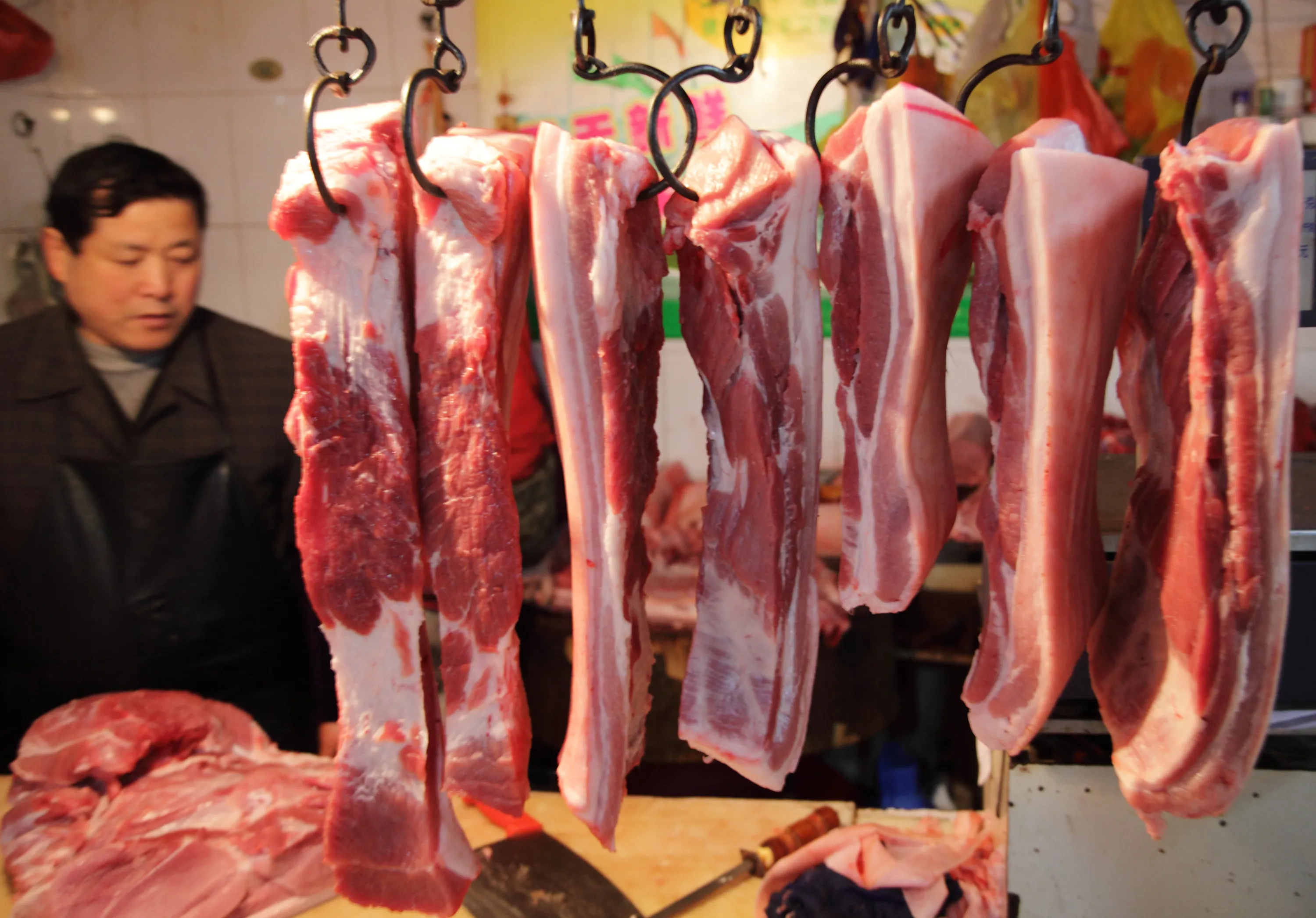 Cuts of pork hang from hooks at a market in Shanghai.&nbsp;