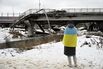 A woman wrapped in Ukrainian flag near a destroyed bridge in Irpin, Ukraine, on Feb. 24.