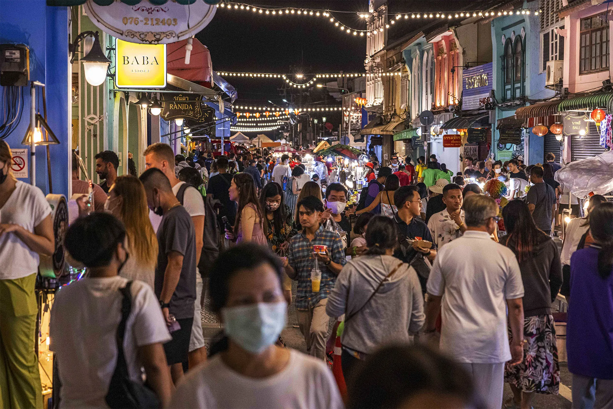 Tourists and locals browse goods and food at a walking street market in Phuket.