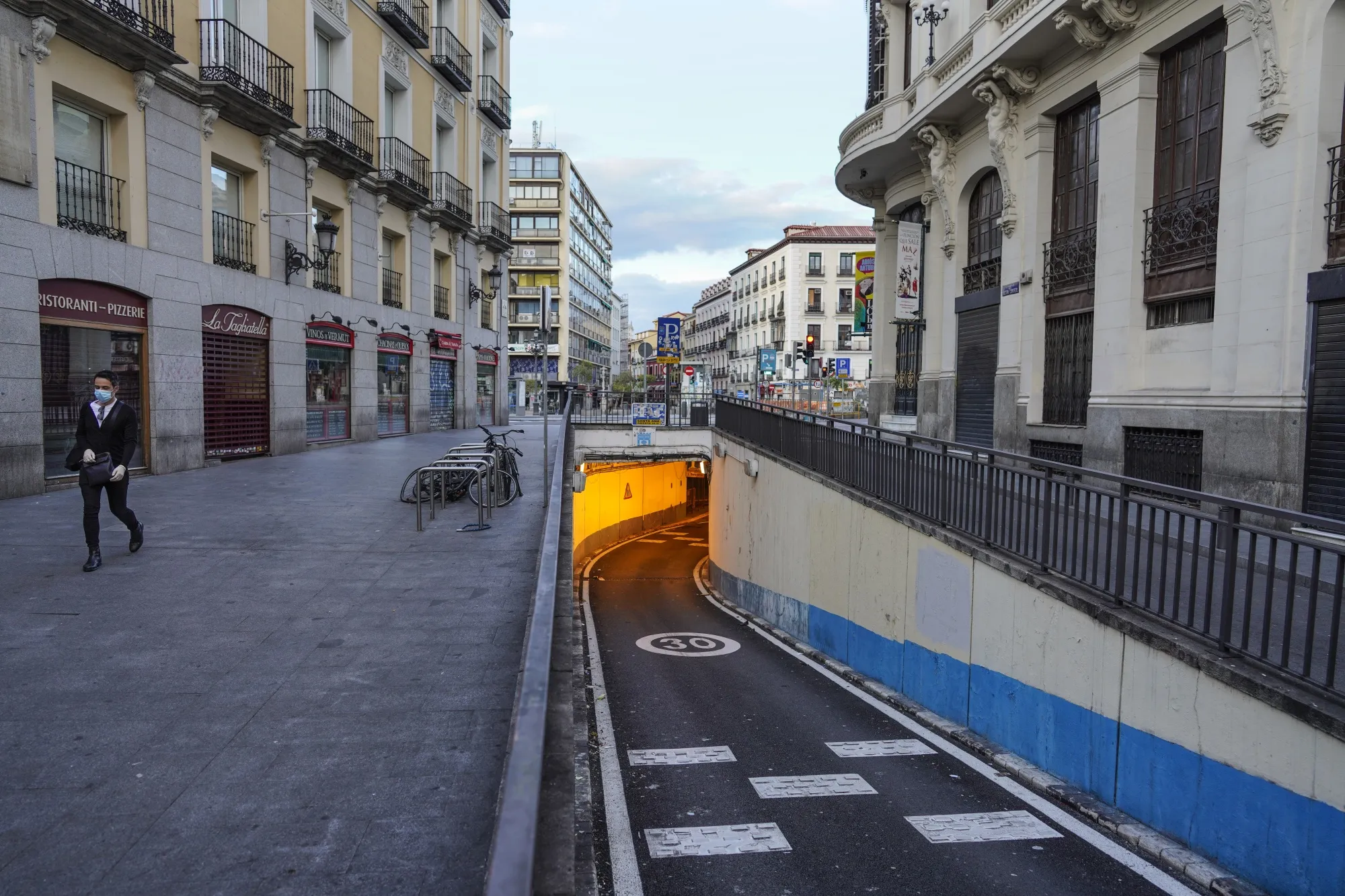 A lone pedestrian wearing a protective face masks walks along an empty precinct in Madrid on April 11.
