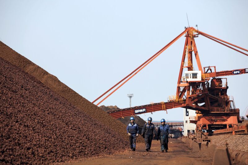 Workers walk past piles of iron ore in Shanghai, China.