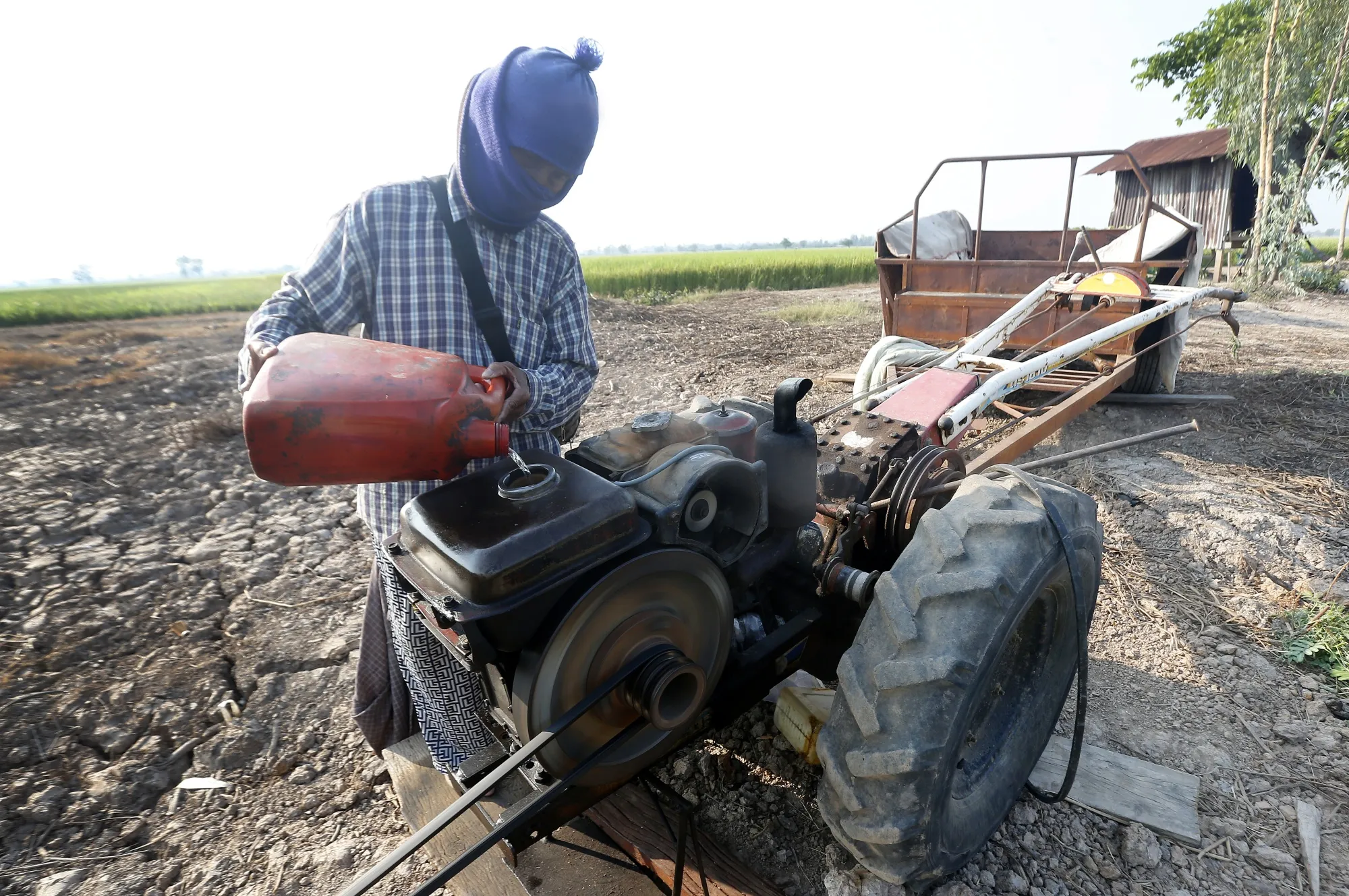 A farmer pours diesel into the engine of a tractor in a field in Phichit province, north of Bangkok, on March 25.