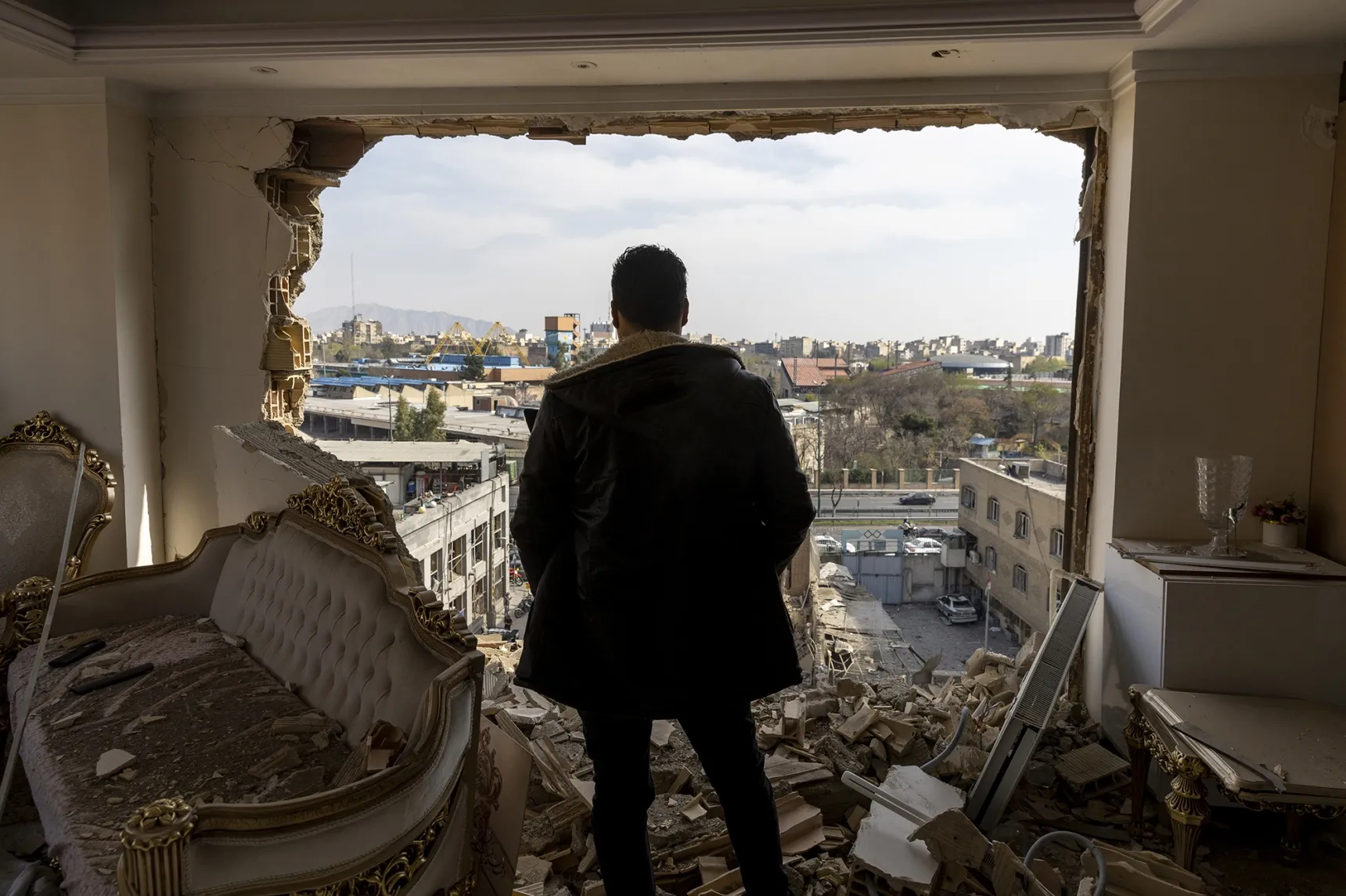 A man stands in a damaged residence following airstrikes in Tehran on March 14.&nbsp;