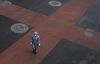 A woman wears a protective suit and mask as she crosses the intersection of a nearly empty street on February 8, 2020 in Beijing.