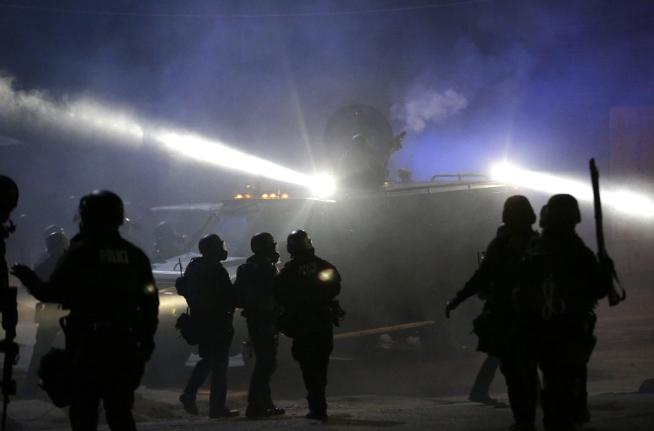 Police in riot gear stand around an armored vehicle as smoke fills the streets in Ferguson, Missouri, after the fatal shooting of Michael Brown by white police officer Darren Wilson.