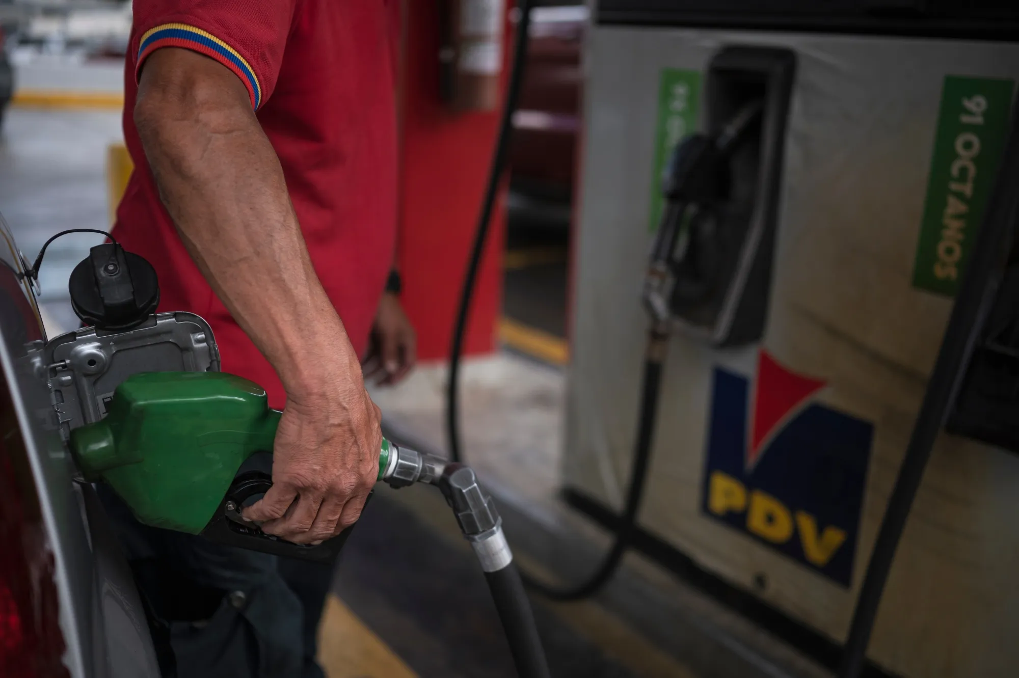 An attendant pumps fuel for a vehicle at a Petroleos de Venezuela gas station in Caracas, Venezuela.