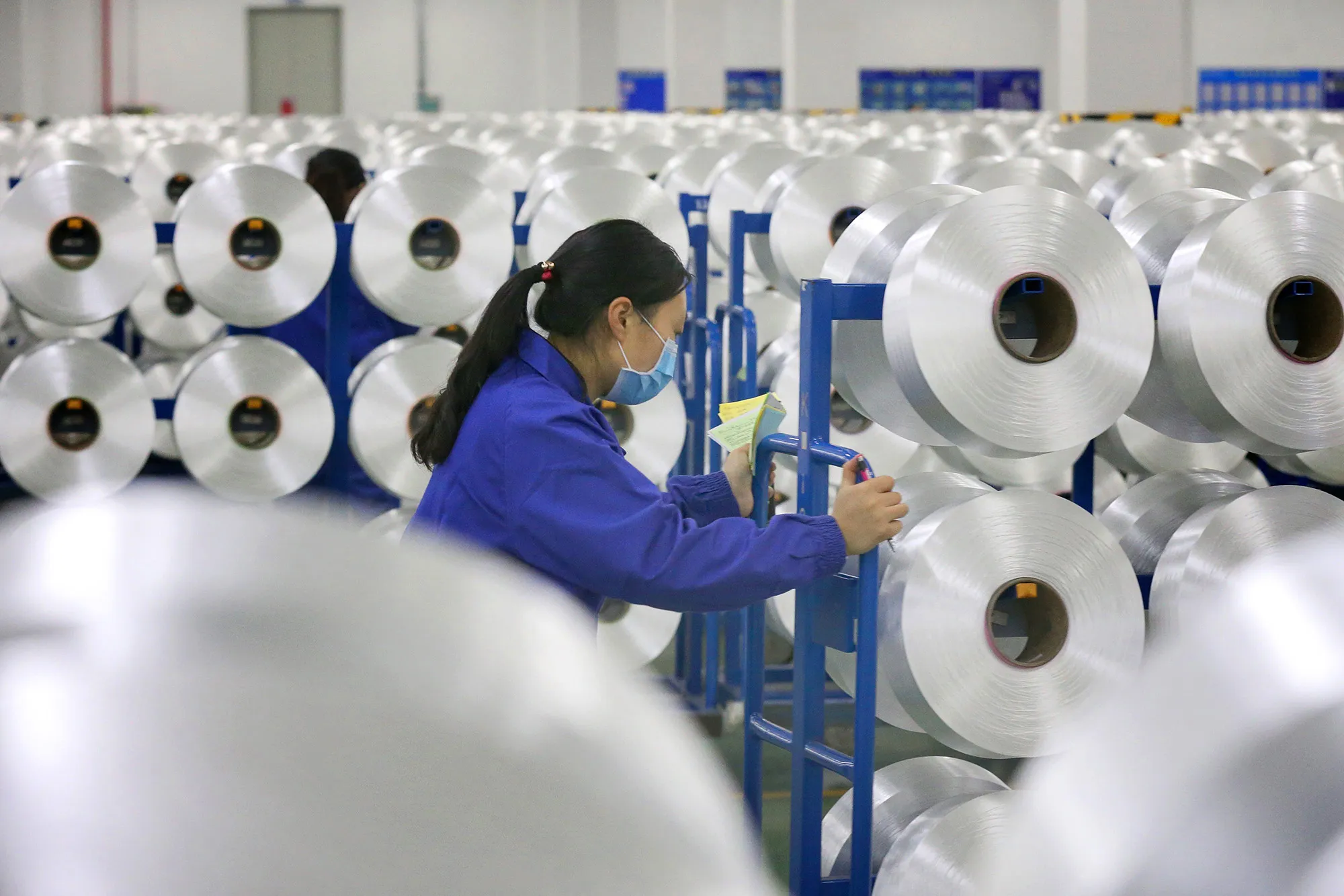 A worker wearing a facemask produces materials that will be used on protective suits at a textile factory in Nantong, China's eastern Jiangsu province.