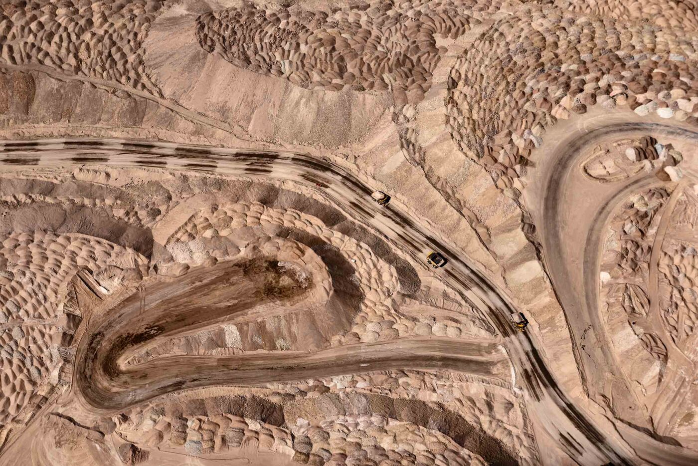卡车从Codelco的Chuquimacata矿的底部运送矿石，这是世界上最大的露天矿。 这里有成堆的尾矿。
