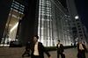 Pedestrians walk past the Mizuho Financial Group Inc. headquarters building at night in Tokyo.