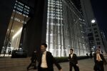 Pedestrians walk past the Mizuho Financial Group Inc. headquarters building at night in Tokyo.