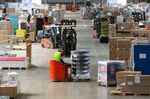 Employees maneuver packages around inside the Kuehne + Nagel International AG logistics center in Haiger, Germany, on Aug. 6.