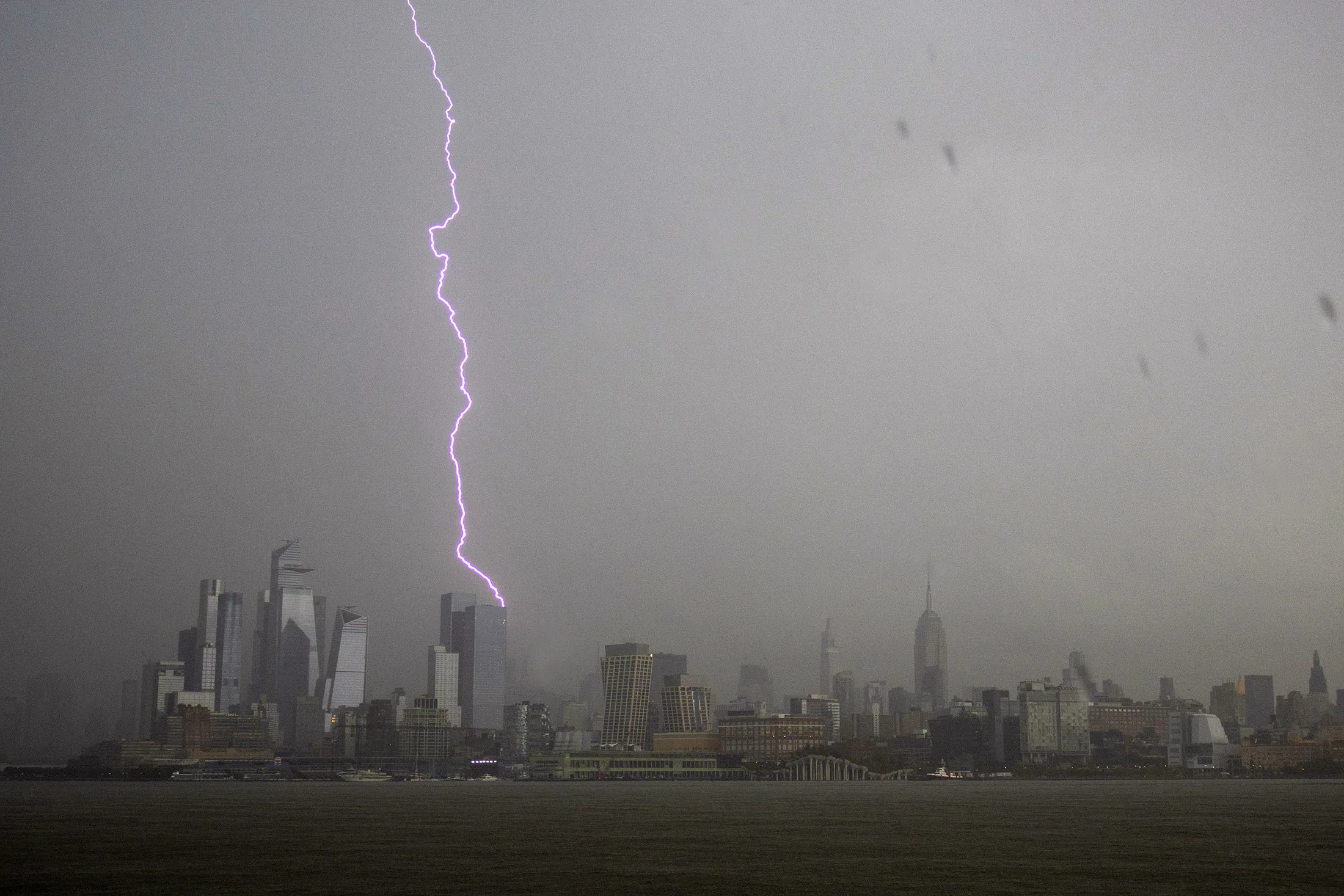 A lightning bolt strikes behind Two Manhattan West and the skyline of midtown Manhattan during a thunderstorm in New York City on July 14, 2023.