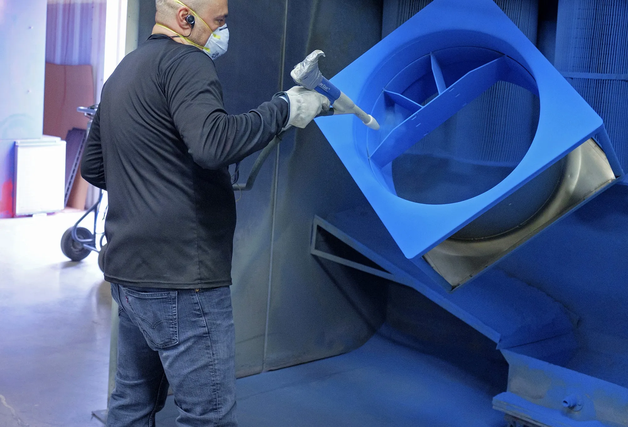 An employee powder coats ventilator components at a production facility in Fort Collins, Colorado.
