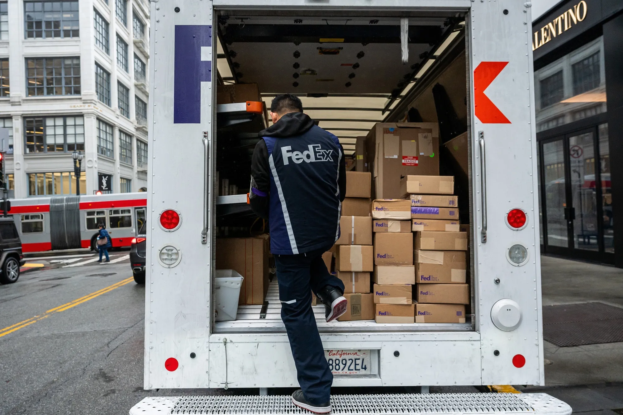 A worker unloads packages from a FedEx truck in San Francisco.
