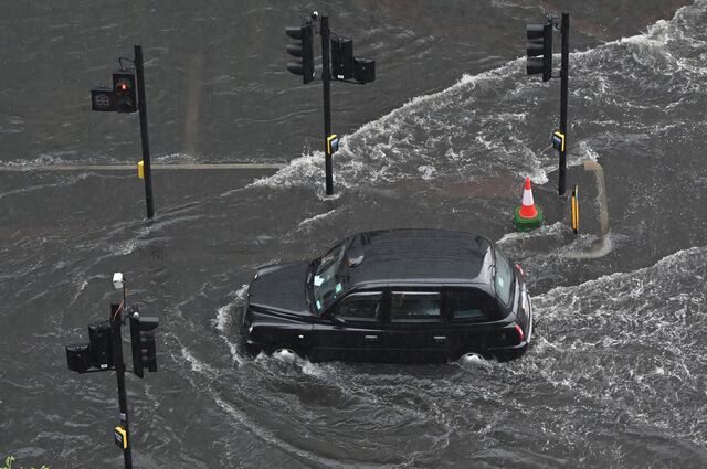 A London taxi drives through water on a flooded road in The Nine Elms district of London on July 25, 2021 during heavy rain.