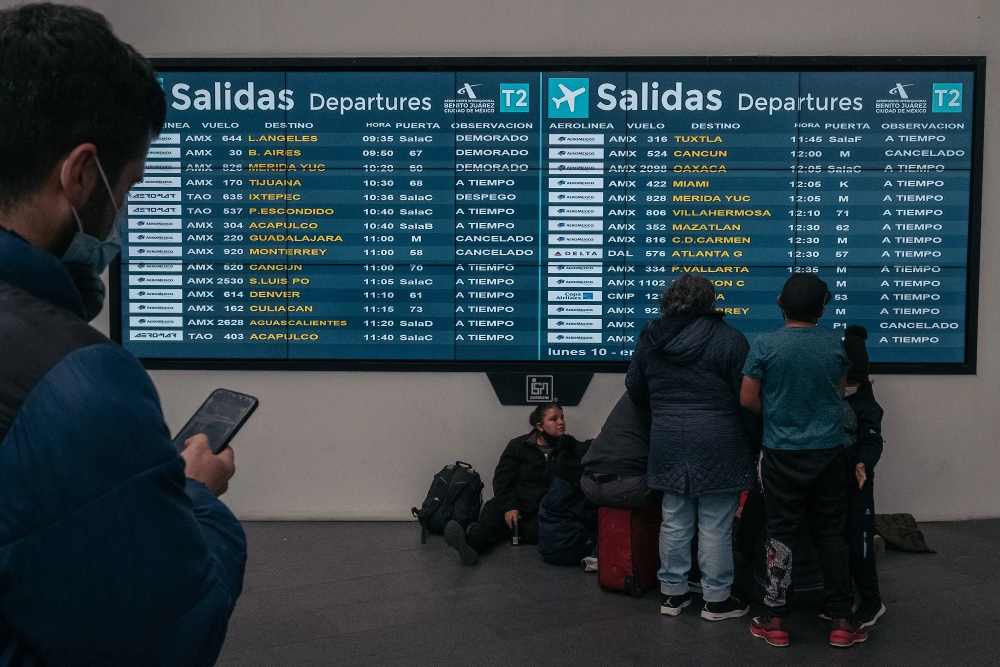 Travelers check the departures board at Benito Juarez International Airport (MEX) in Mexico City, Mexico, on Monday, Jan. 10, 2022.&nbsp;
