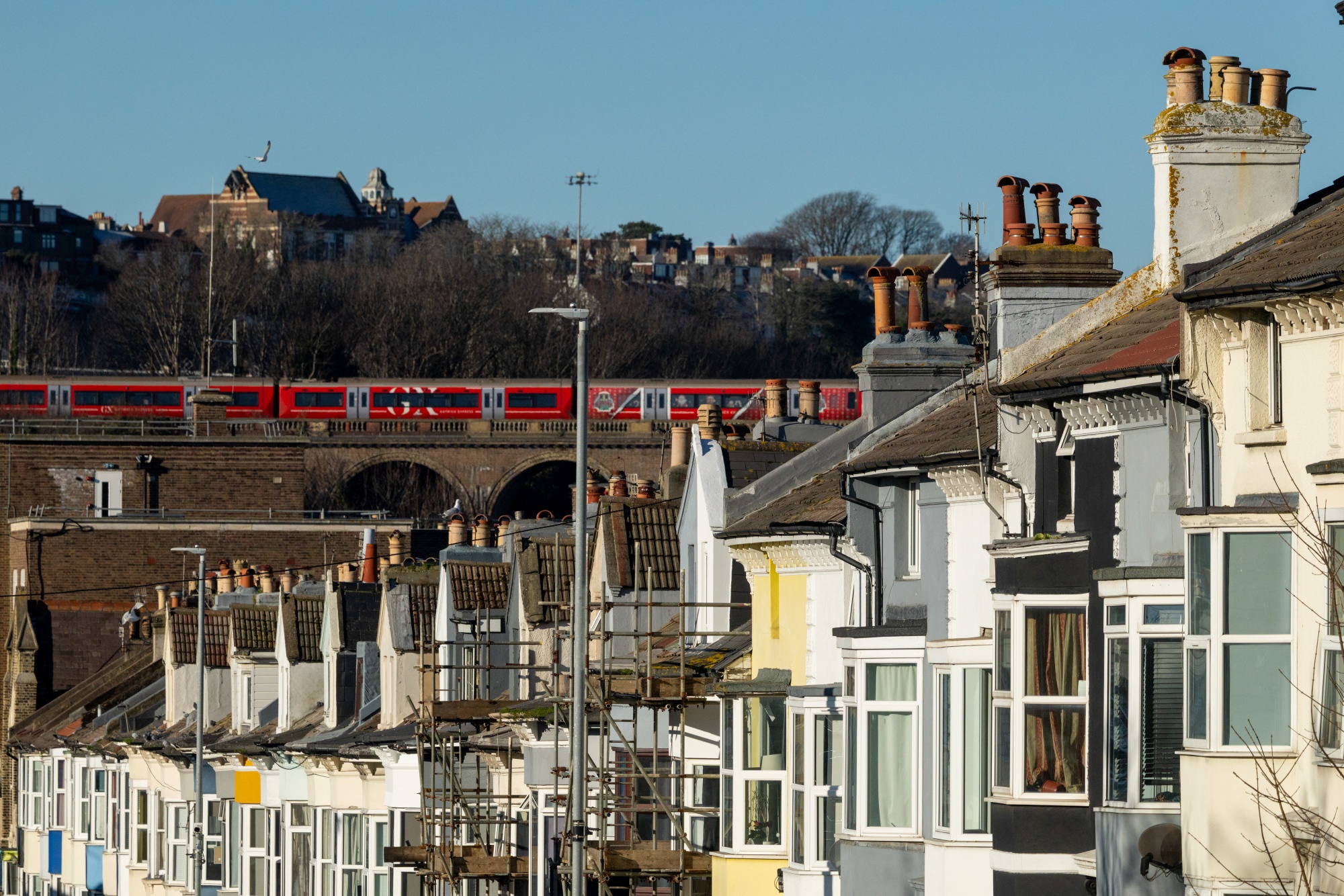 A passenger train on a viaduct passing residential housing in Brighton, UK.