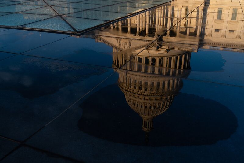The Capitol building reflected in a puddle in Washington, DC, US.
