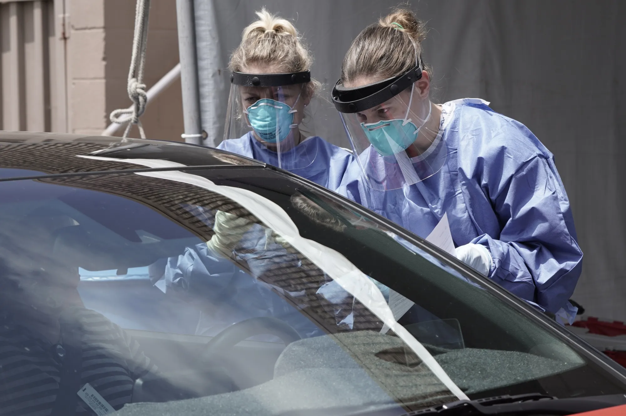 Nurses wearing personal protective equipment speak with a patient at a Covid-19 drive-through testing site at the North Inland Live Well Escondido Center in Escondido, California, U.S., on Thursday, April 30, 2020.&nbsp;