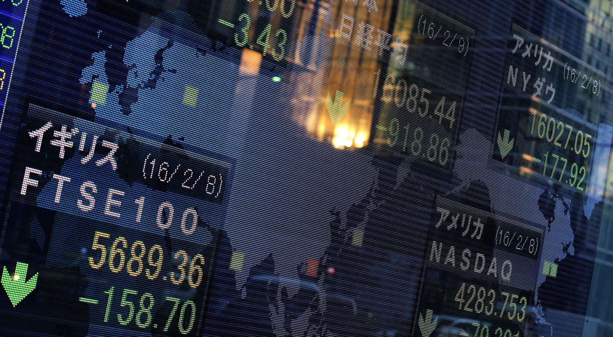 A reflection of a setting sun on a building is seen in front of a glass of an electronic monitor displaying the closing price of the Nikkei 225 Stock Average outside a securities firm in Tokyo.
