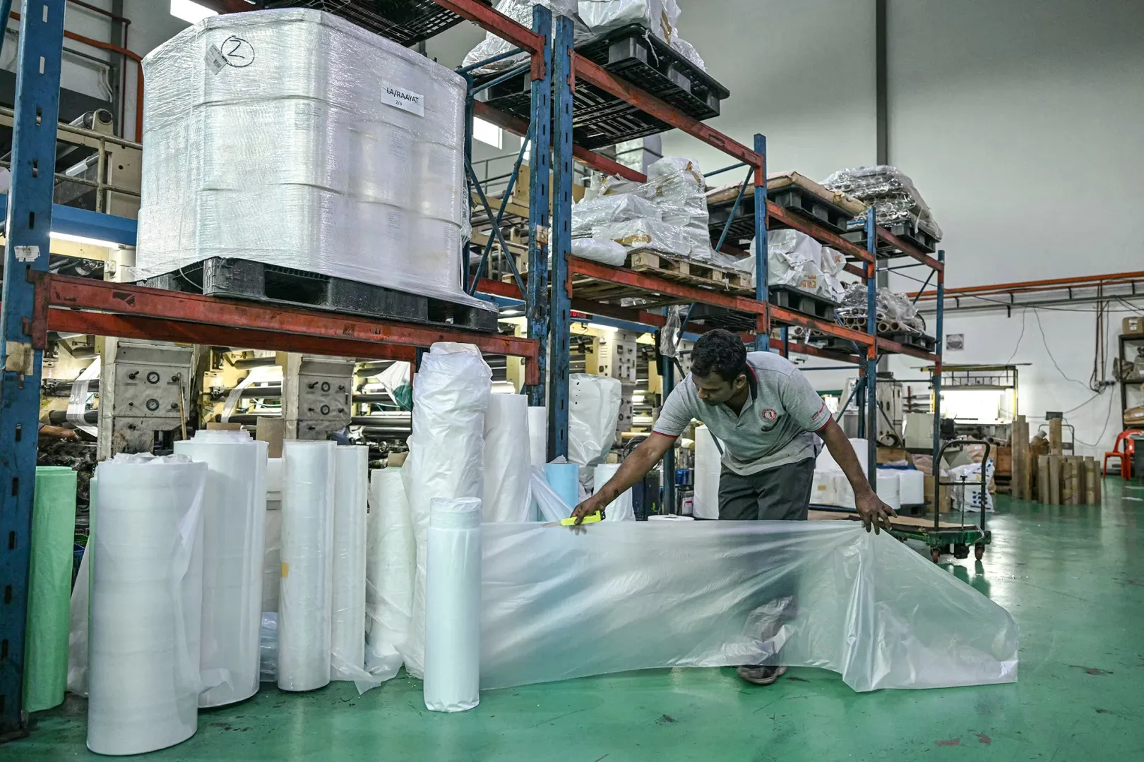 A worker inspects polyethylene plastic products at a plastic factory in Klang, Malaysia.