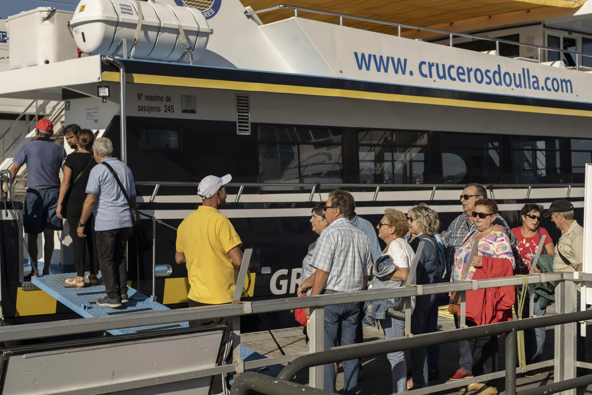 Tourists queue to board a cruise boat at the port in O Grove, Spain.