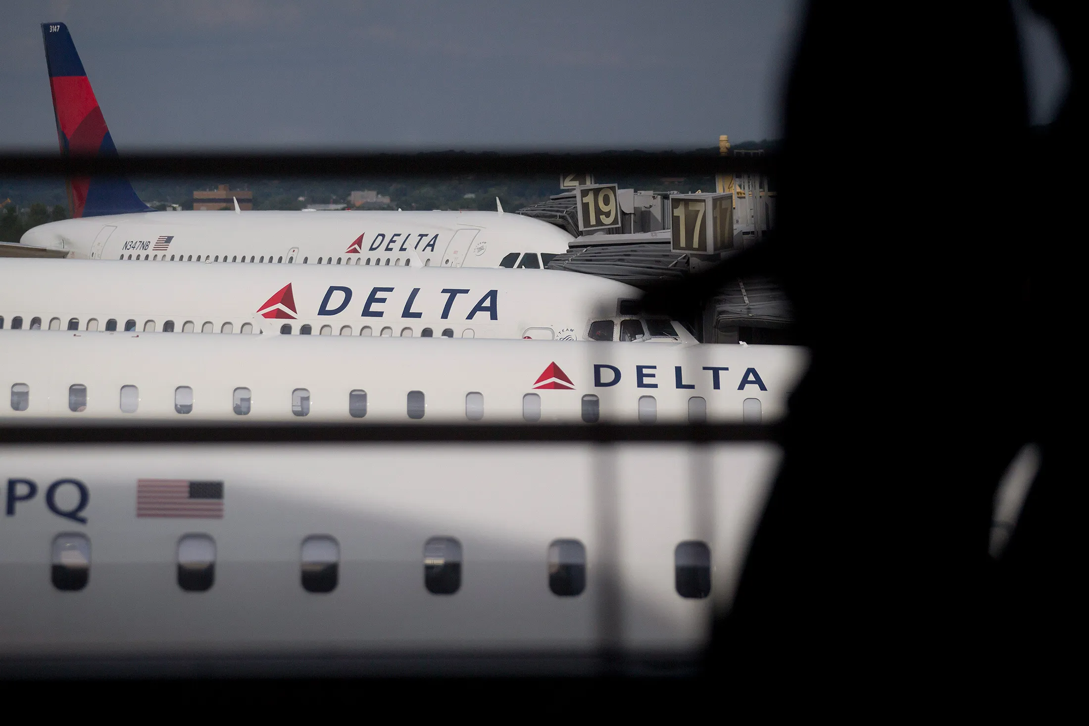 The silhouette of a traveler is seen walking past Delta Air Lines Inc. airplanes parked at gates of Ronald Reagan National Airport in Washington, D.C., U.S., on Wednesday July 16, 2014.
