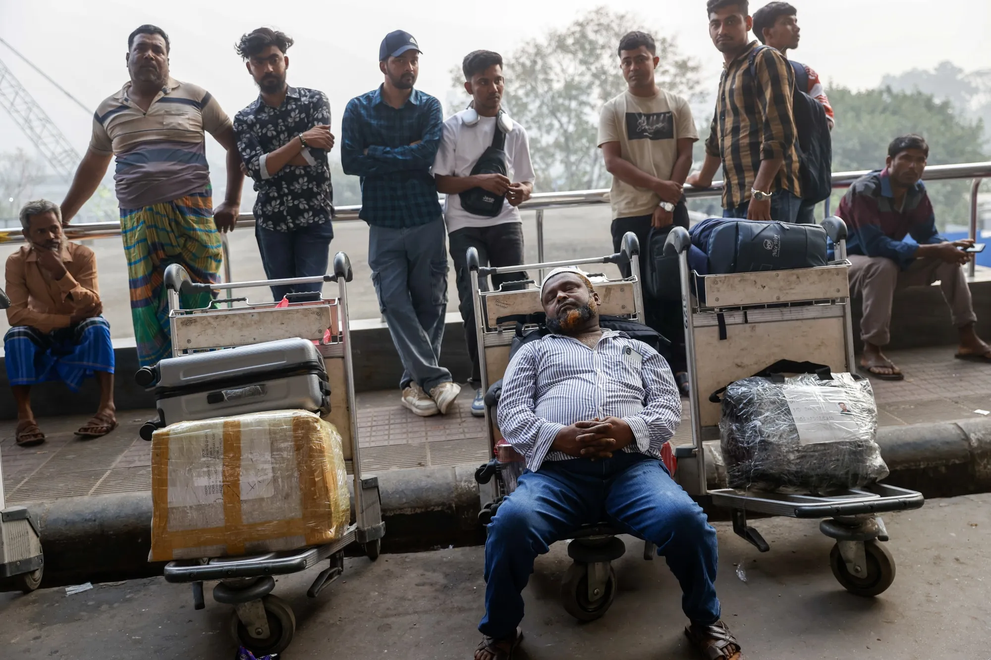 Passengers and their relatives wait outside the terminal after several flights to Middle Eastern destinations were canceled in Dhaka, Bangladesh, in March.