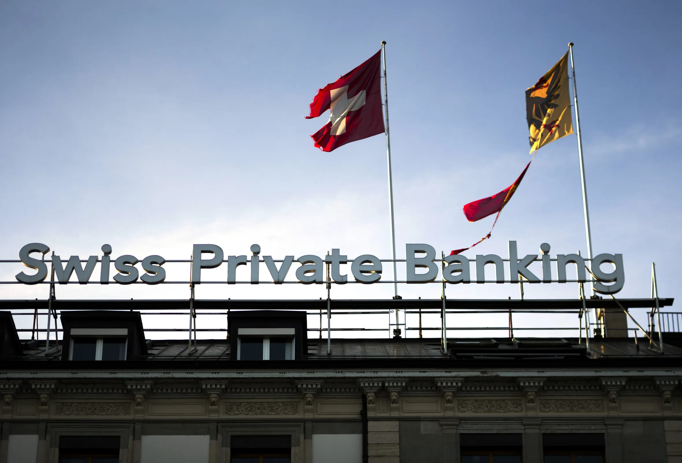 The Swiss national flag&nbsp;flies alongside the Geneva Canton flag&nbsp;on top of the Bank Hapoalim&nbsp;(BHI) offices in Geneva, Switzerland.