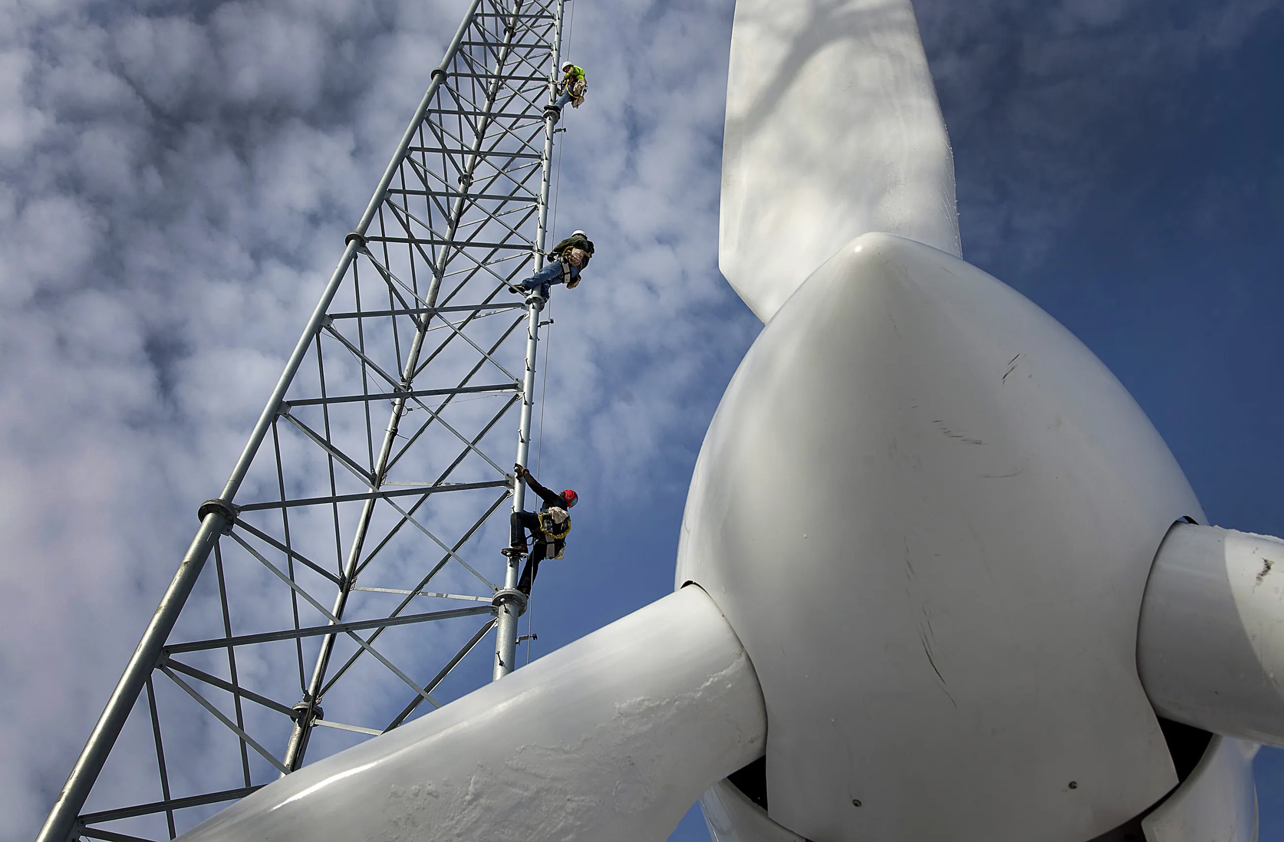 Tower Men Climb a Tower Near a Wind Turbine