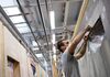 A worker prepares the section edge of a wall unit under construction for a pre-fabricated home at the Danwood SA factory in Bielsk Podlaski, Poland