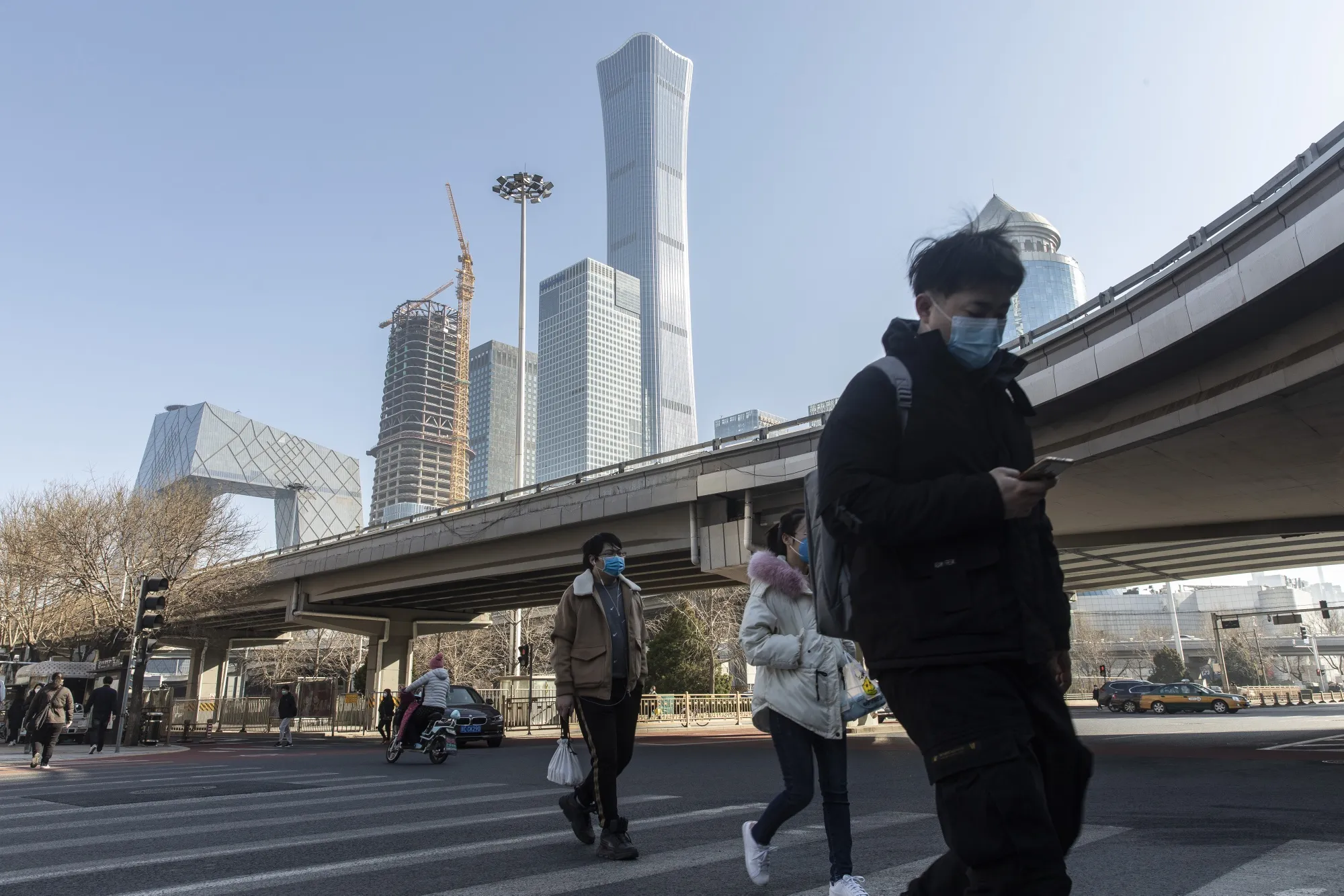 Commuters wearing protective masks cross a road in the business district in Beijing, China, on&nbsp;March 17.