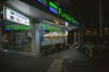 People sit outside of a Family Mart near Phrom Phong ahead of a temporary curfew imposed due to the coronavirus in Bangkok, Thailand, on Friday, April 3, 2020. The Thai government may consider imposing a 24-hour curfew if daily coronavirus cases continue to rise after night time restrictions were announced today.