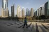 A pedestrian walks on an elevated walkway past buildings in Pudong's Lujiazui Financial District in Shanghai, China, on Friday, Dec. 28, 2018. China announced plans to rein in the expansion of lending by the nation's regional banks to areas beyond their home bases, the latest step policy makers have taken to defend against financial risk in the world's second-biggest economy.