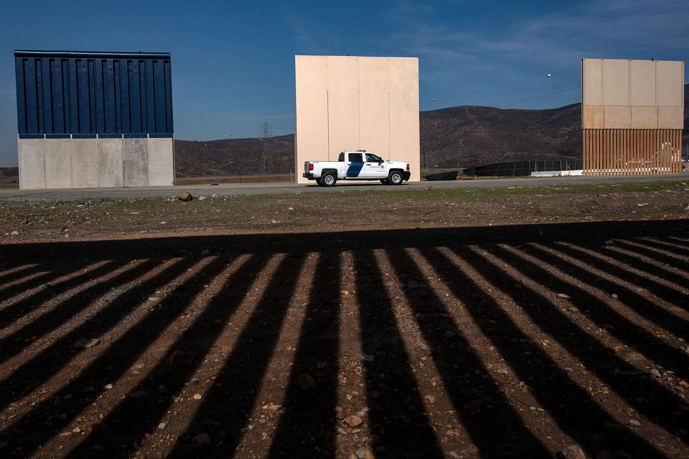 A Customs and Border protection vehicle passes by Donald Trump's wall prototypes.