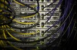 Network cables sit connected to servers in a computer room.