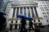 Pedestrians carrying umbrellas pass in front of the New York Stock Exchange (NYSE) in New York, U.S., on Thursday, March 29, 2018. U.S. stocks climbed as markets moved toward the end of a tumultuous quarter on a high note. Equities in Europe also rose following a mixed session in Asia.