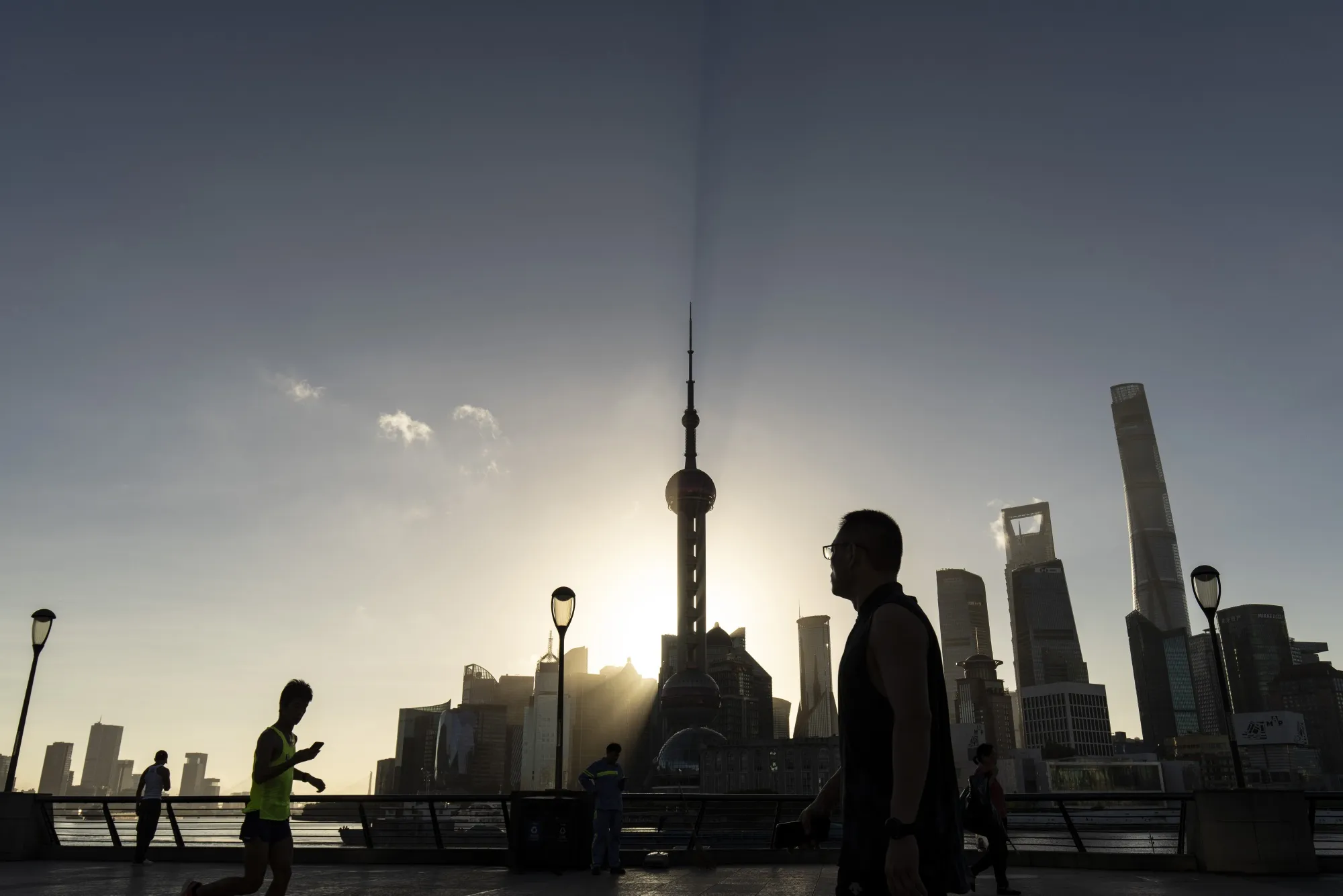 Pedestrians along the Bund across from commercial buildings in Pudong's Lujiazui Financial District in Shanghai.