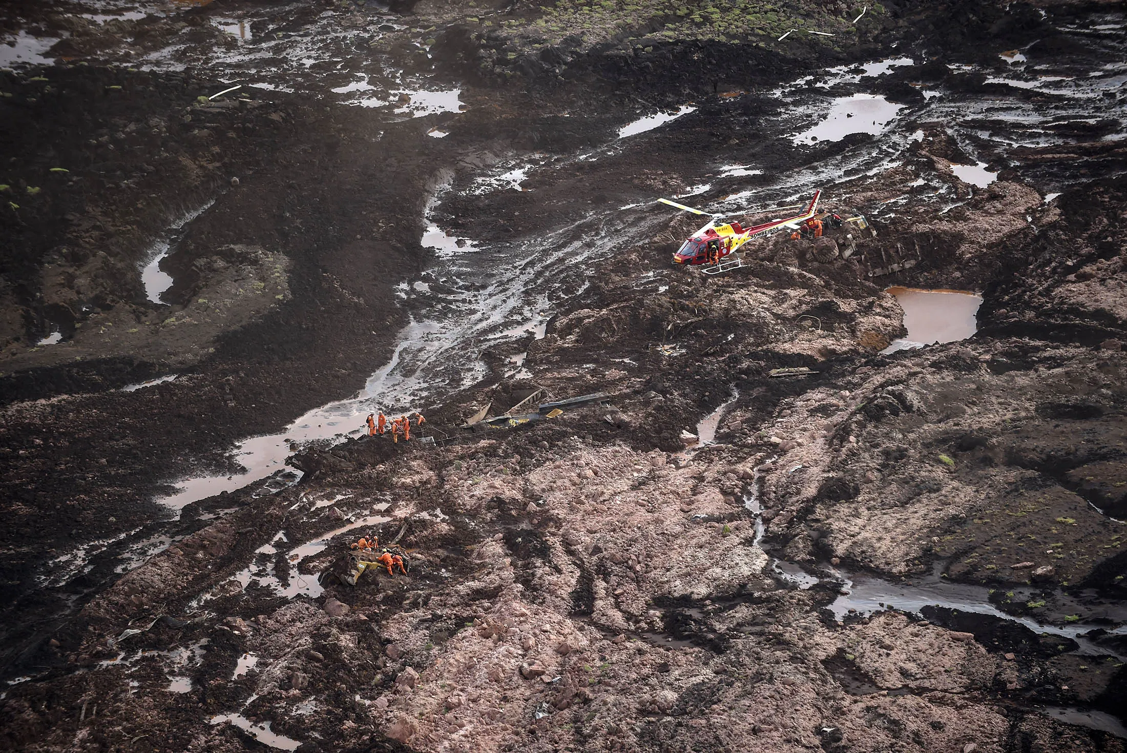 A firefighters' helicopter overflies the area as rescuers work in the search for victims after the collapse of a dam, which belonged to Brazil's giant mining company Vale, near the town of Brumadinho in southeastern Brazil, on January 25, 2019. - A dam collapse in southeast Brazil unleashed a torrent of mud on a riverside town and surrounding farmland Friday, destroying houses, leaving 200 people missing and raising fears of a number of deaths, according to officials. (Photo by Douglas Magno / AFP) (Photo credit should read DOUGLAS MAGNO/AFP/Getty Images)