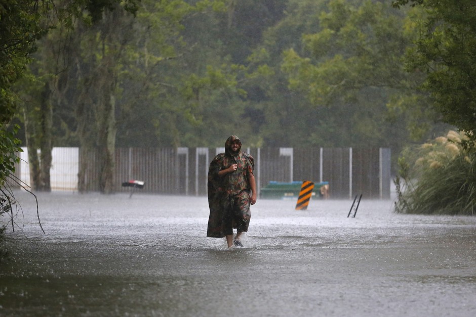 A man walks through flood waters and rain in St. Amant, Louisiana.