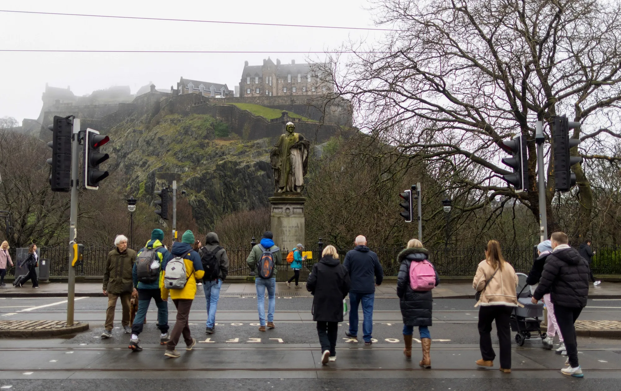 Pedestrians cross a road near Edinburgh Castle in Edinburgh, UK.