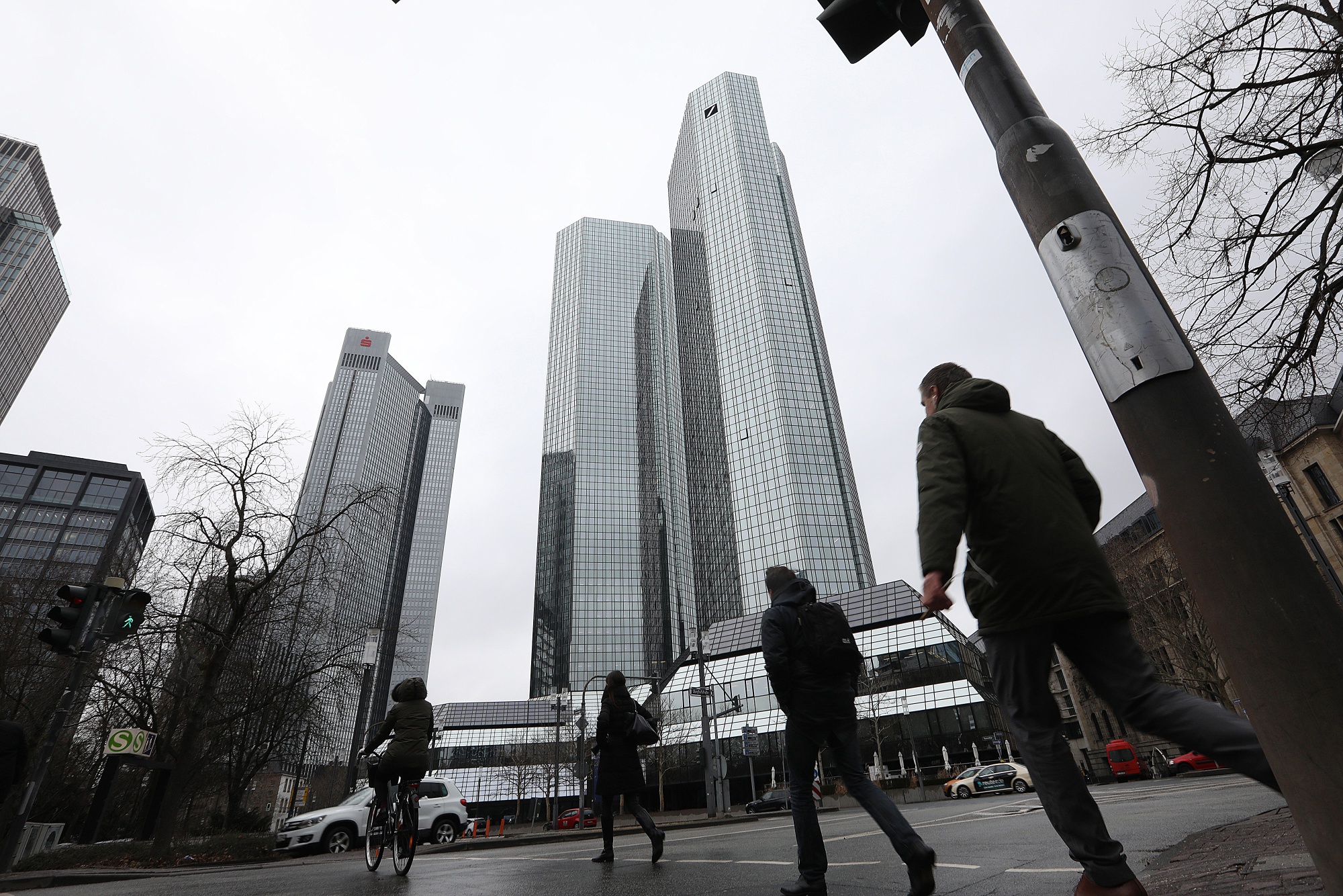 Pedestrians cross a road in front of the Deutsche Bank AG headquarters in Frankfurt.