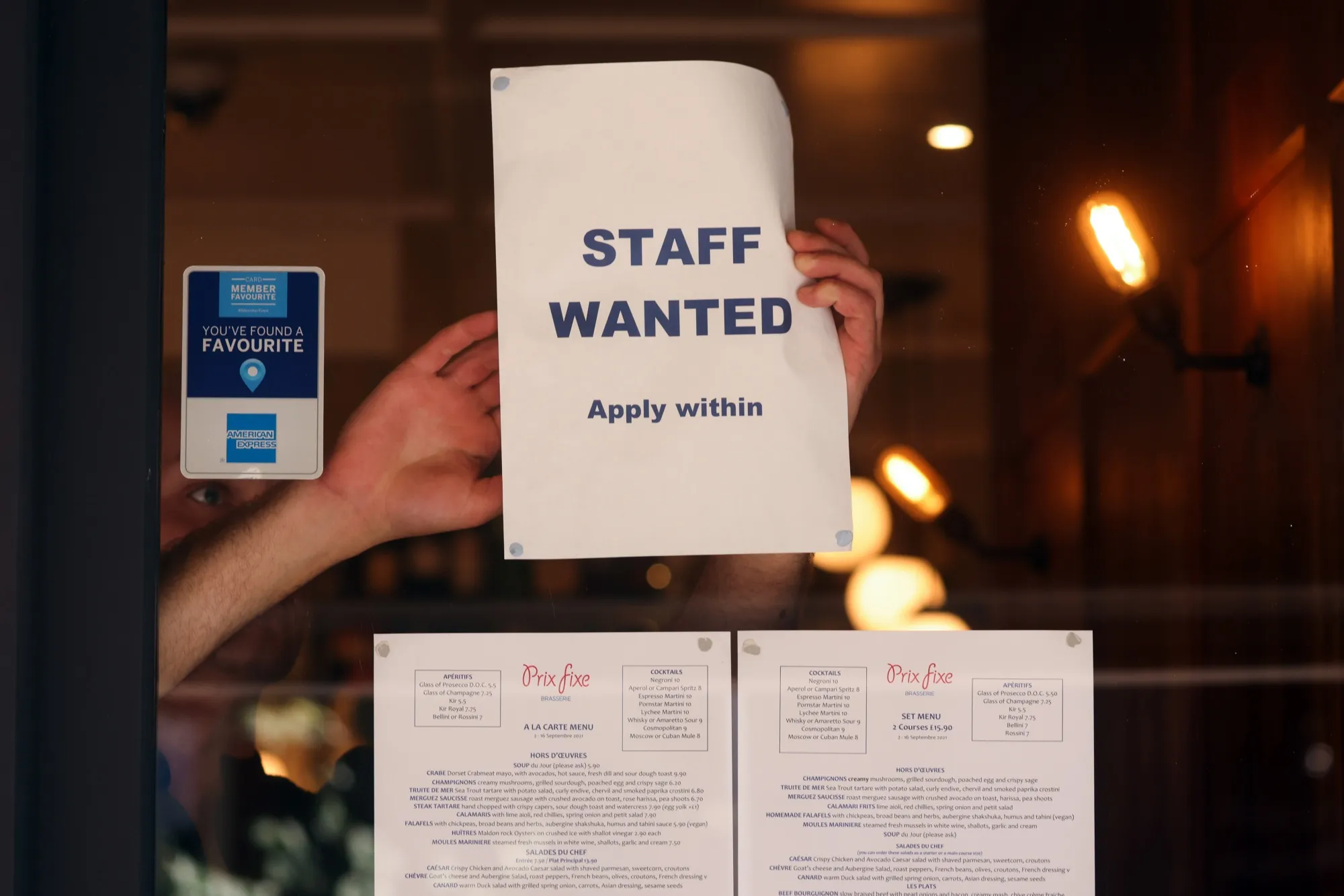 A staff wanted sign in the window of a restaurant in the Soho district of London.
